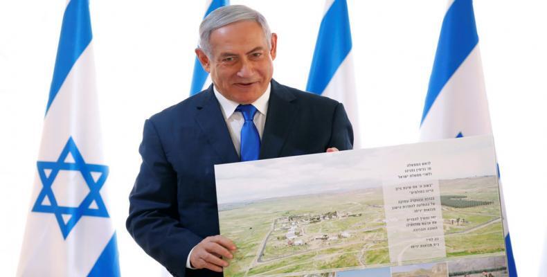 Benjamin Netanyahu poses with a placard given while visiting a Jordan Valley settlement.  (Photo: © REUTERS/Amir Cohen)